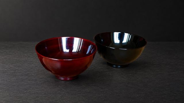 Two tame-nuri urushi bowls: on the left, after years of use, warm red showing through; on the right, new and near-black