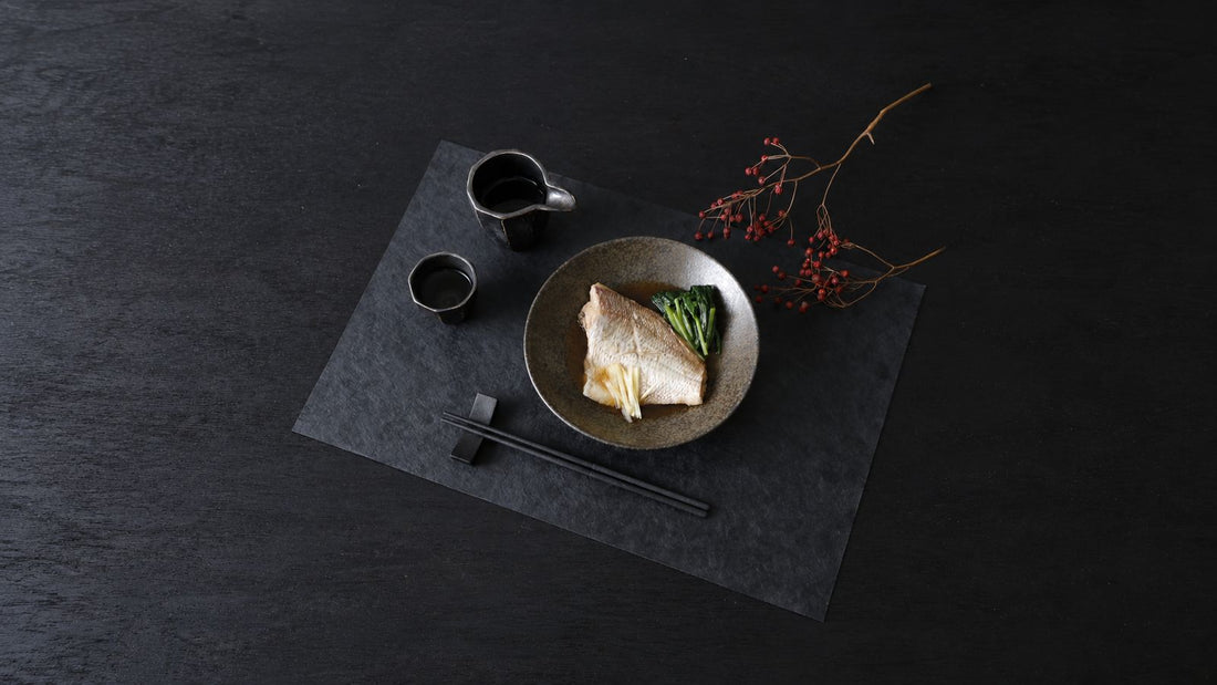A Japanese fish dinner with urushi-finished chopsticks on a rest and a washi placemat