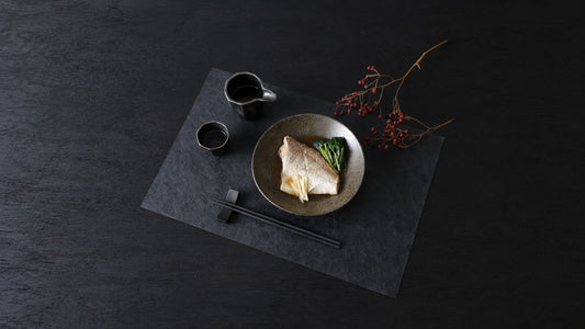 A Japanese fish dinner with urushi-finished chopsticks on a rest and a washi placemat