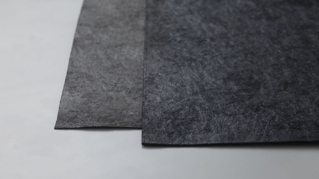 Two overlapping sheets of urushi-finished Mino washi showing the fibrous texture of the paper