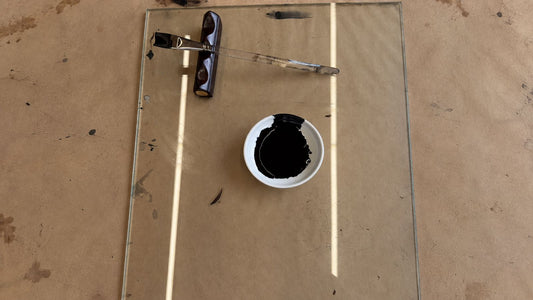 Raw urushi lacquer in a small white dish with a lacquer brush on a glass work surface in the workshop