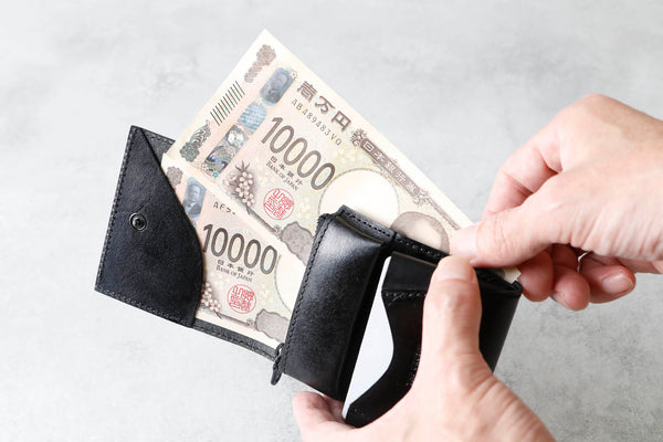 お札を出し入れしている手元。大きく開く設計が伝わるカット。
