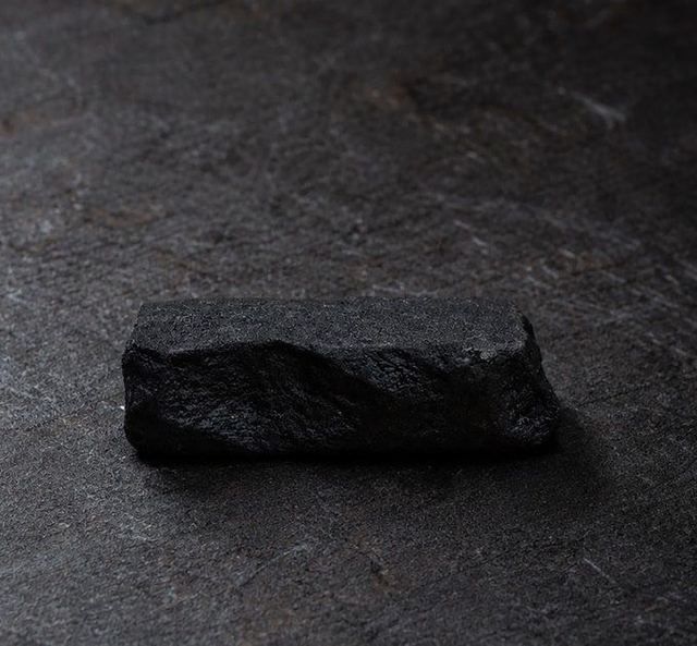 A rough-cut black stone chopstick rest by INASE, finished in heat-cured urushi